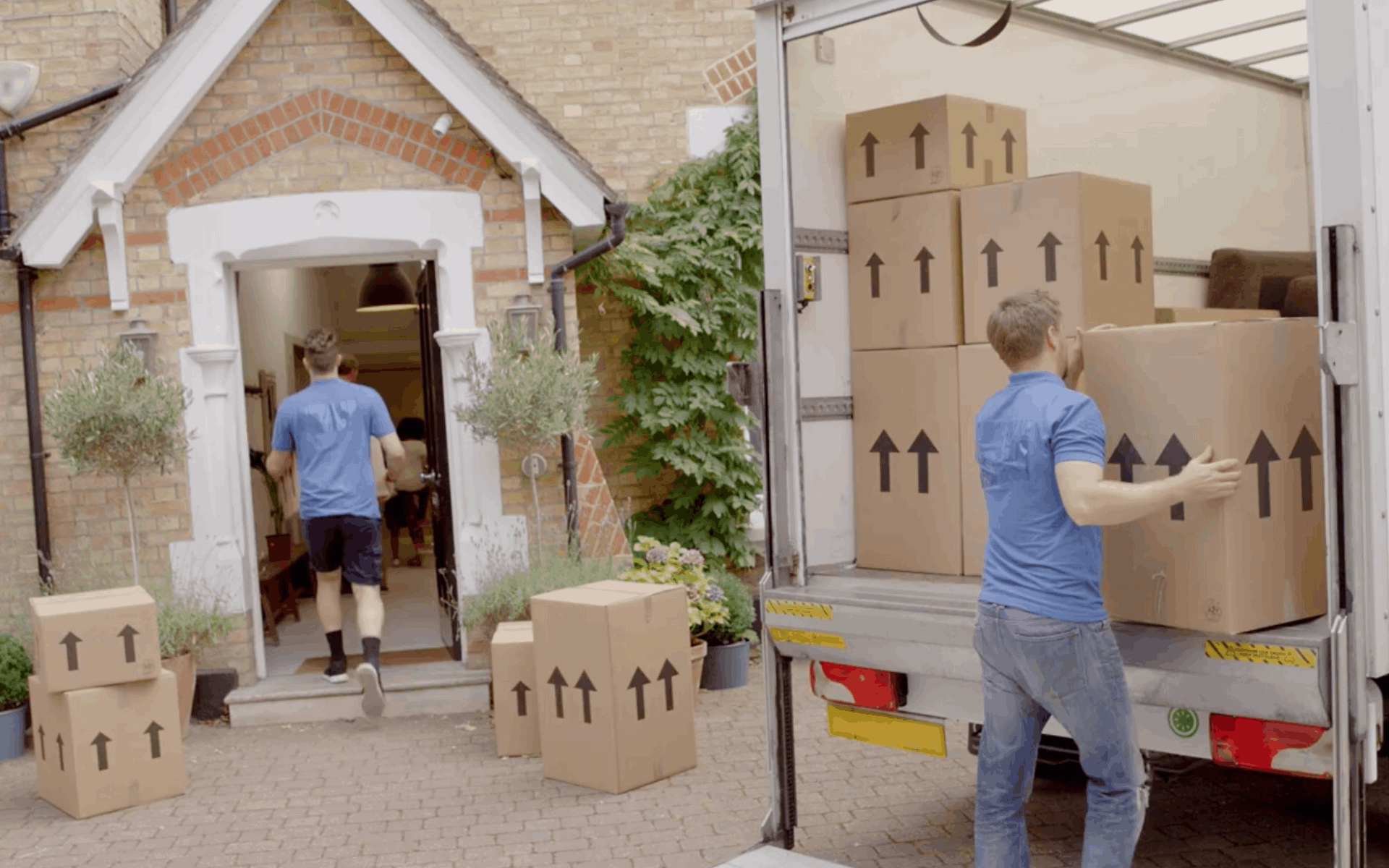 Movers carrying boxes from a truck into a house